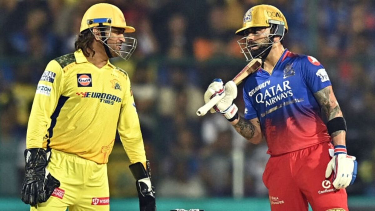 Virat Kohli and MS Dhoni smiling and greeting each other during an IPL match, representing RCB and CSK.